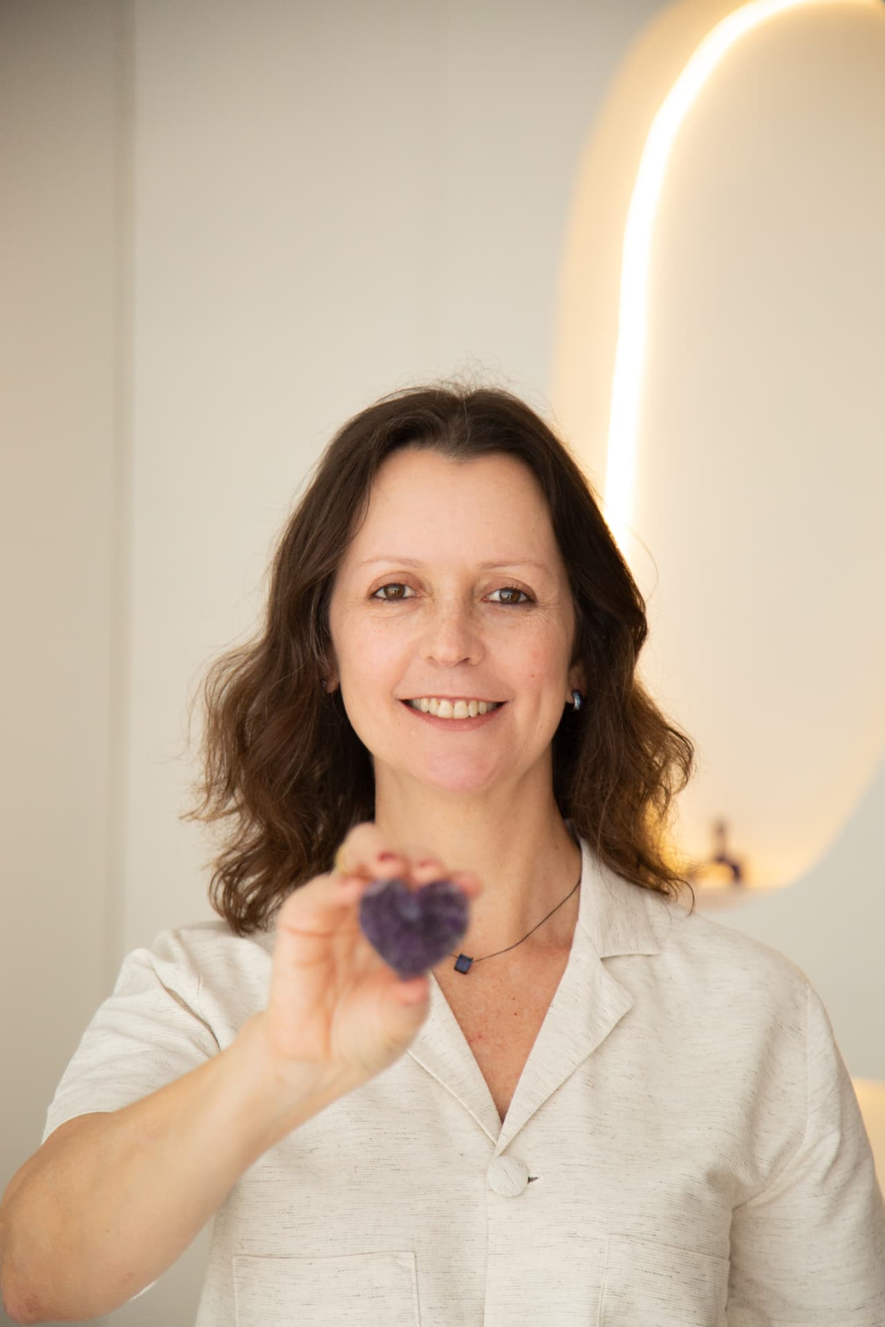 Luciane segurando uma pedra de ametista em formato de coração